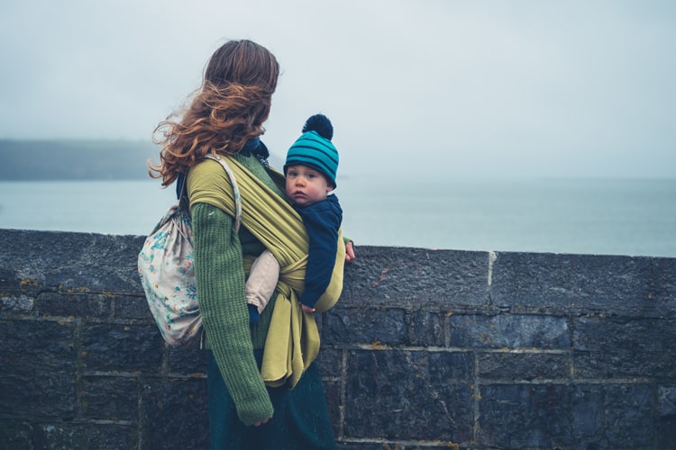 Mother Carrying Baby Travel Companion By The Water On Vacation