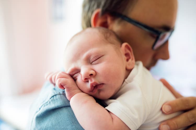 Father Holding Baby Travel Companion As He Sleeps On Daddy'S Shoulder