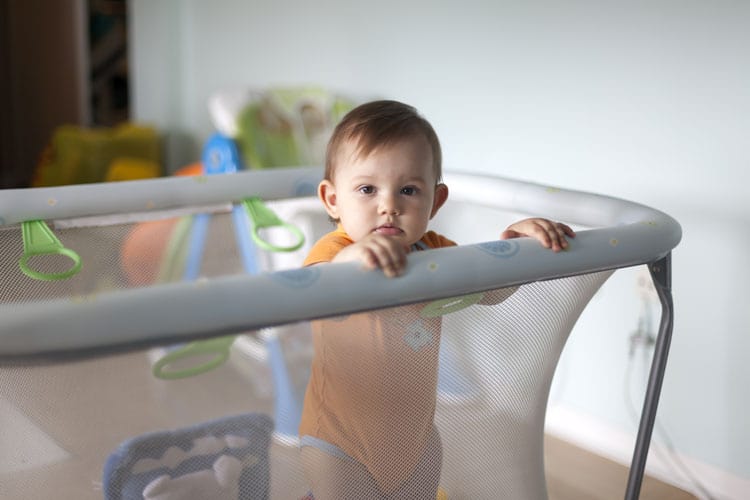 baby standing in pack 'n play