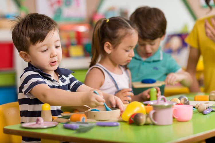 Children Sitting At Table Practicing The Montessori Method