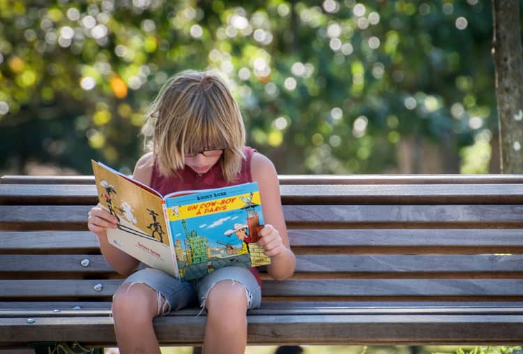 Child Reading A Book Outside