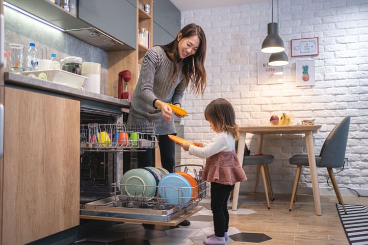 Small Child Putting Dishes In Dishwasher